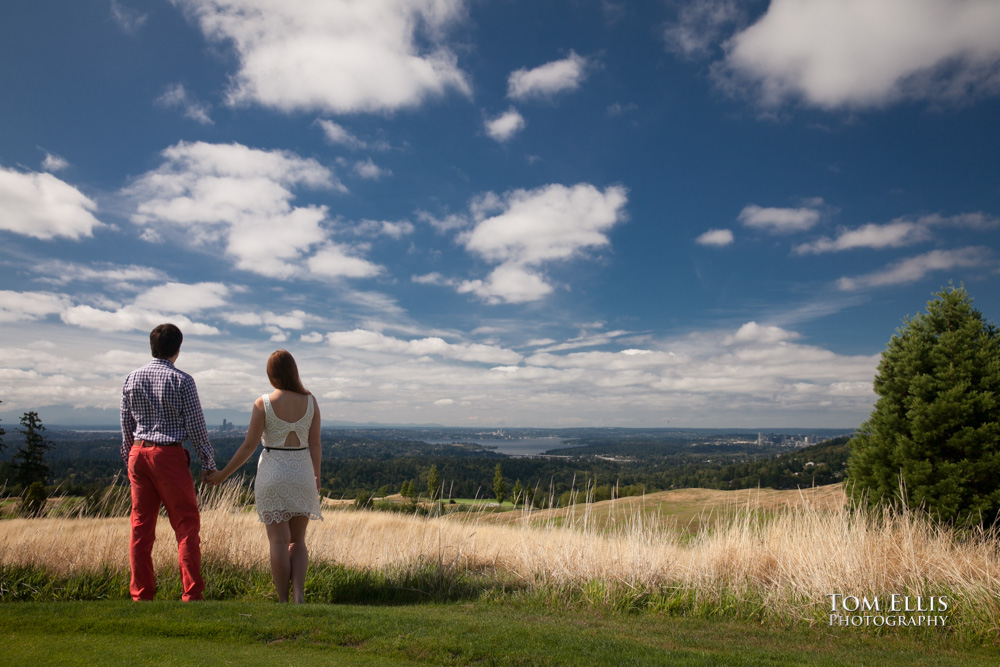 Romantic photo of couple looking out over Newcastle Golf Club, blue sky and big white clouds