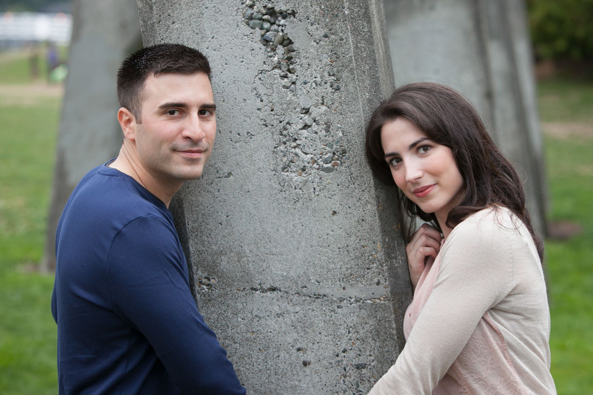 Couple holding hands in front of concrete arches at Gasworks Park engagement photo session