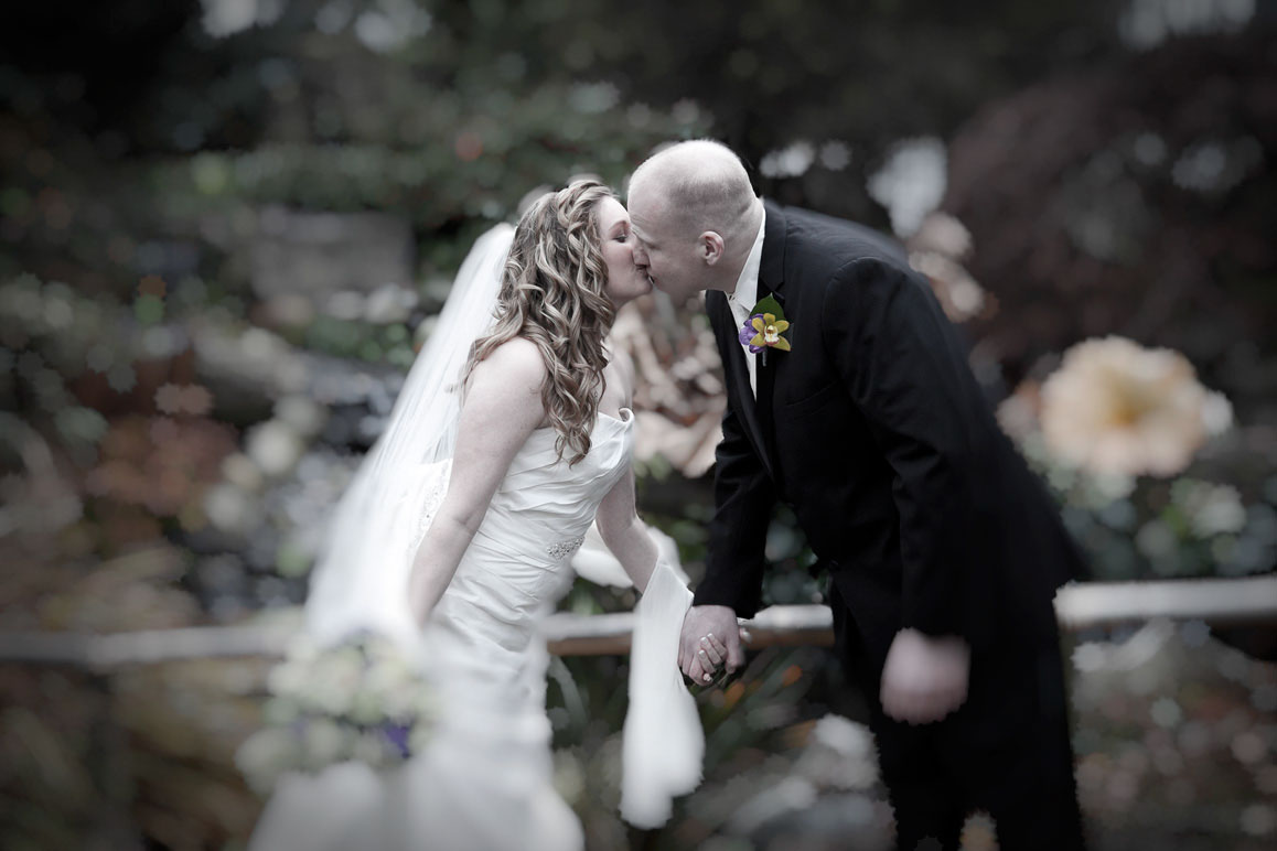 Soft-focus photo of bride and groom kissing at Windmill Gardens