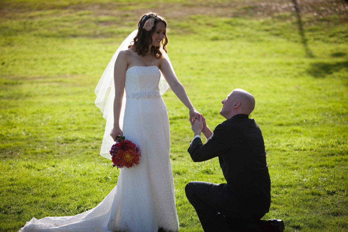 Groom kneeling in front of bride holding her hand at Hamilton Overlook in Seattle