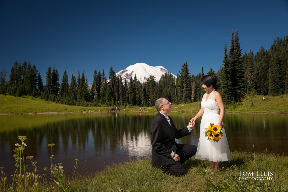 Marty kneels in front of his new wife Pat at Tipsoo Lake with Mt Rainier in the background