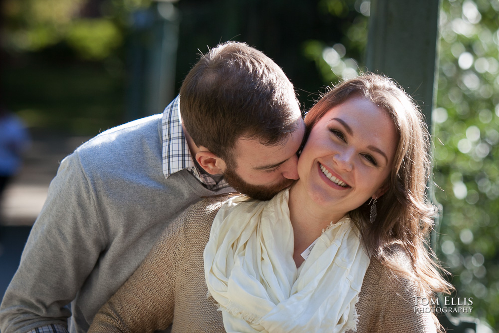 Justin gives Ashley a kiss on the neck while she smiles at the photographer