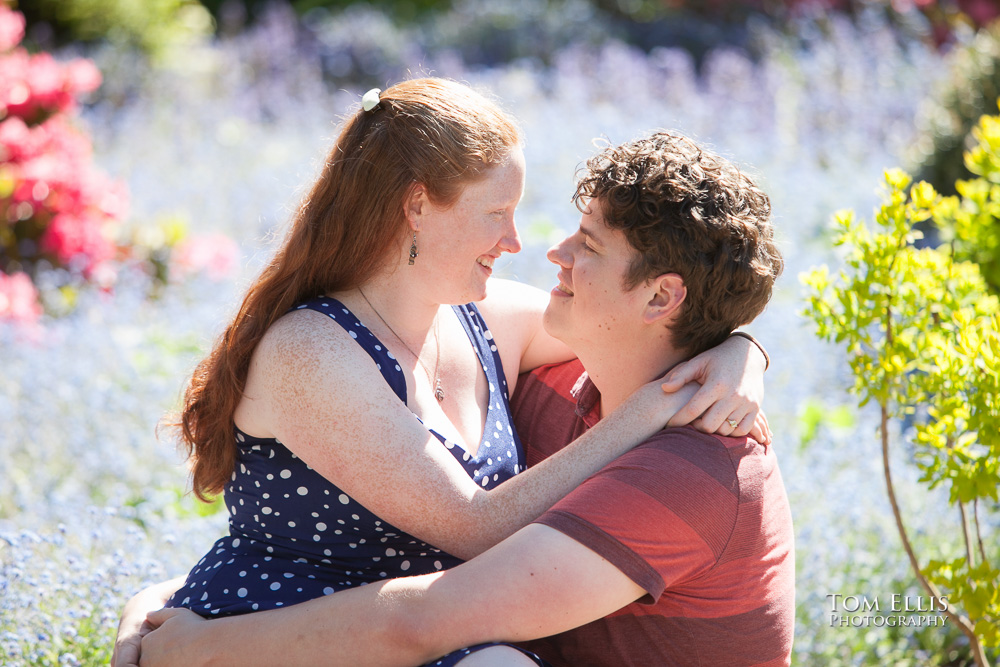 Close up photo of couple sitting in patch of forget-me-not flowers during their Seattle engagement photo session at Kubota Garden