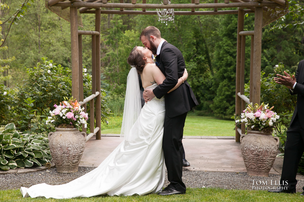 Bride and groom kiss at the conclusion of the wedding ceremony at an outdoor garden venue