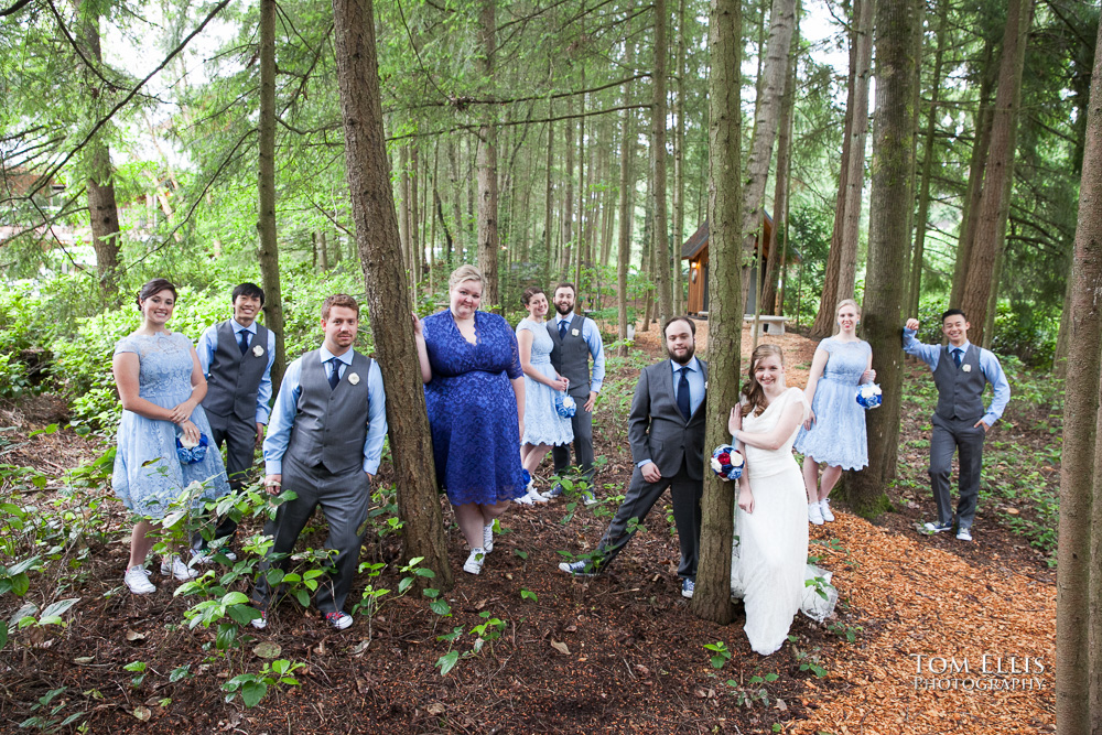 Bride, groom and their wedding party pose for a photo in the forest