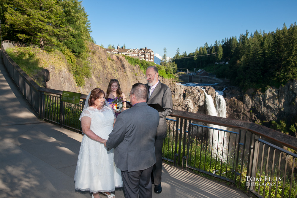 Bride and groom hold hands as they say their wedding vows during their wedding ceremony at Snoqualmie Falls.