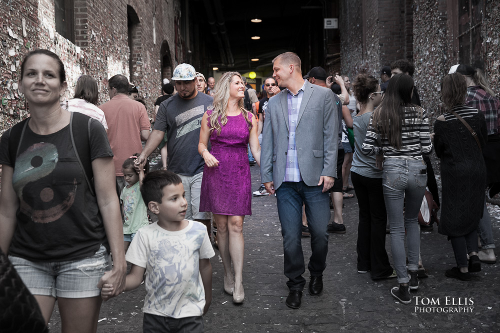 Engaged couple walking through a crowd of people at Pike Place Market in Seattle, couple is in full-color, others are desaturated