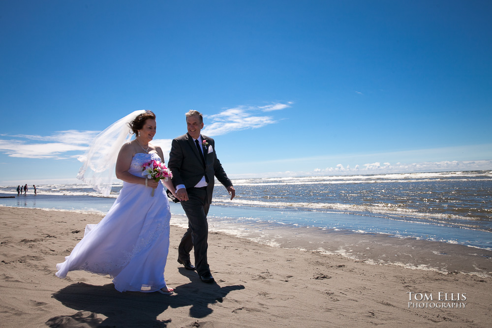 Bride and groom walk along the beach at Ocean Shores