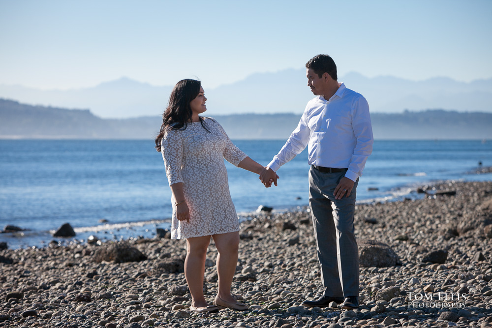 Couple standing hand-in-hand on beautiful beach, with view across Puget Sound to the Olympic Mountains