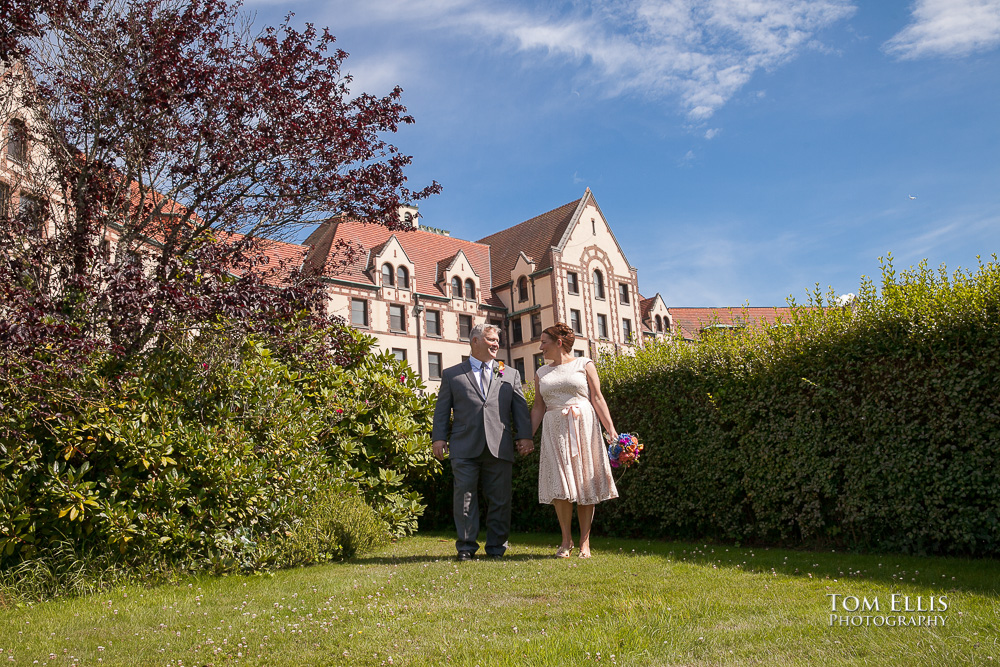 Bride and groom walk together in beautiful garden before their Seattle wedding ceremony