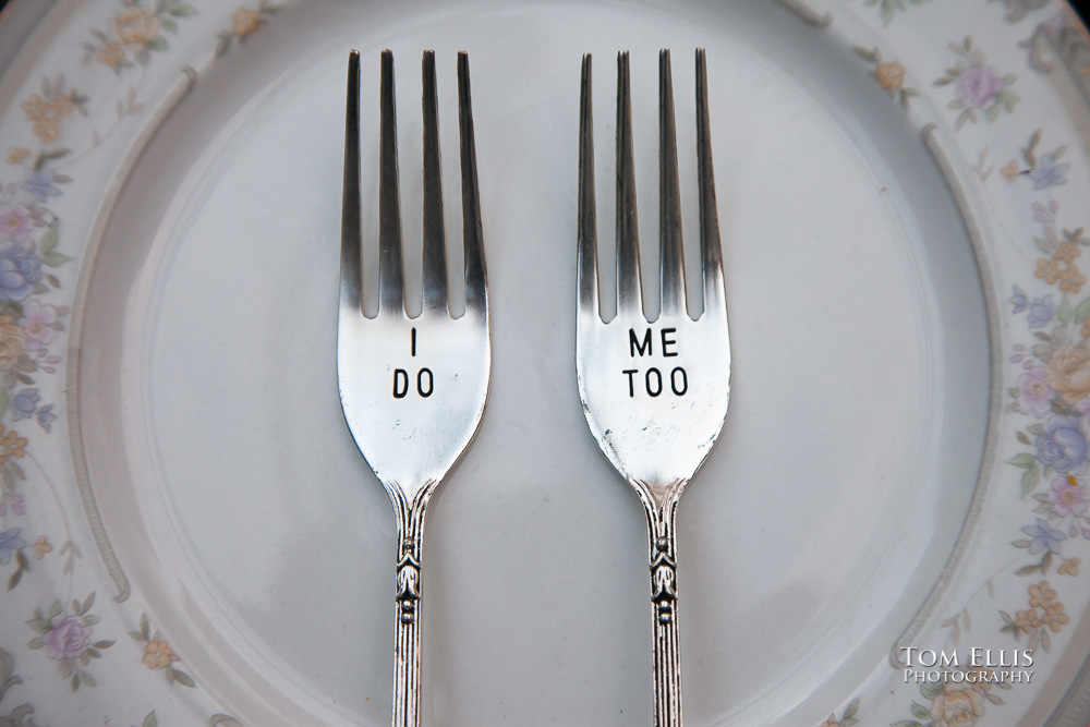 Wedding close-up photo of two engraved forks, one with "I Do" and the other with "Me Too" engraved on them.