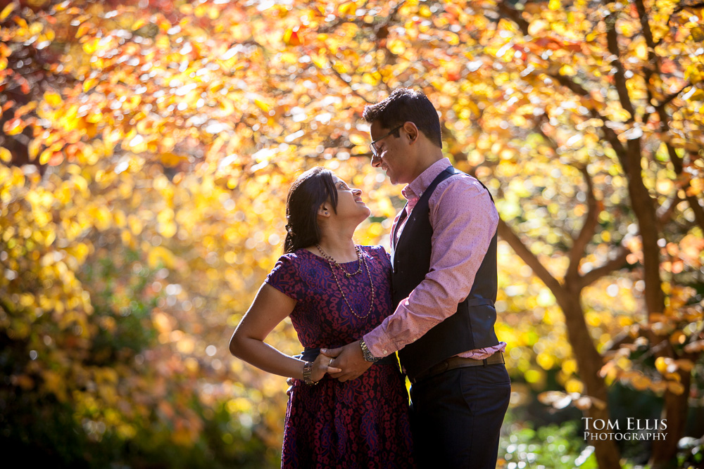 Couple poses against a background of brilliant yellow autumn foliage at the Washington Arboretum during their Seattle engagement photography session with Tom Ellis Photography