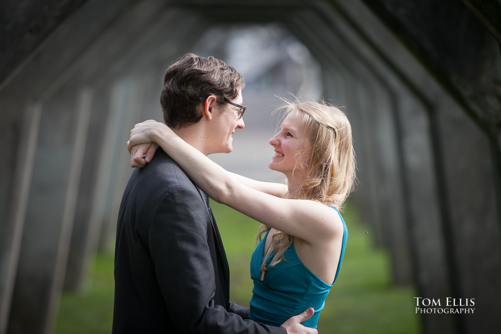 Engagement photo of couple hugging under the old concrete arches at Gasworks Park in Seattle