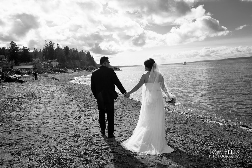 Romantic black and white photo of bride and groom walk along the beach in Mukilteo before their Seattle area wedding