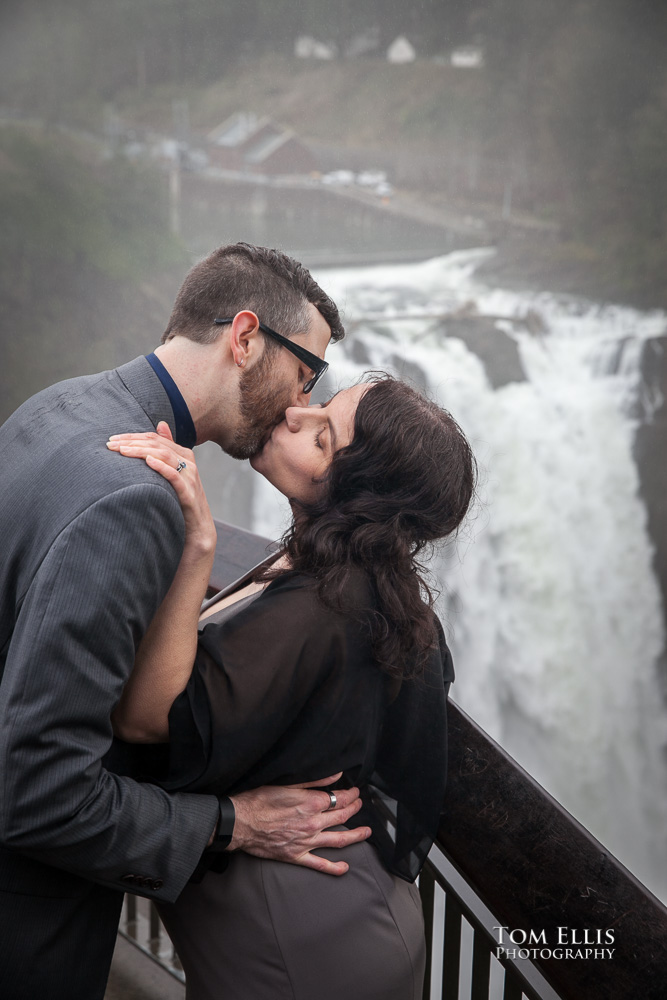 Just married couple kiss on the viewpoint overlooking Snoqualmie Falls at the conclusion of their elopement wedding