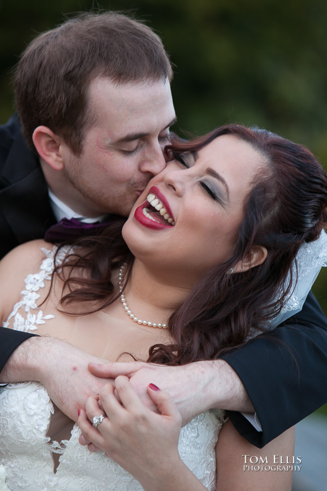 Close up photos as groom hugs laughing bride from behind while he gives her a kiss on the cheek