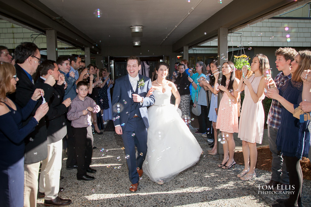 Newlywed couple leaves the church at the conclusion of the wedding reception, and they are bombarded with bubbles blown by the guests to say goodbye