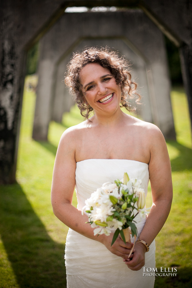 Bride Alyssa stands framed by the concrete arches of Seattle's Gas Works Parks for this wedding day portrait