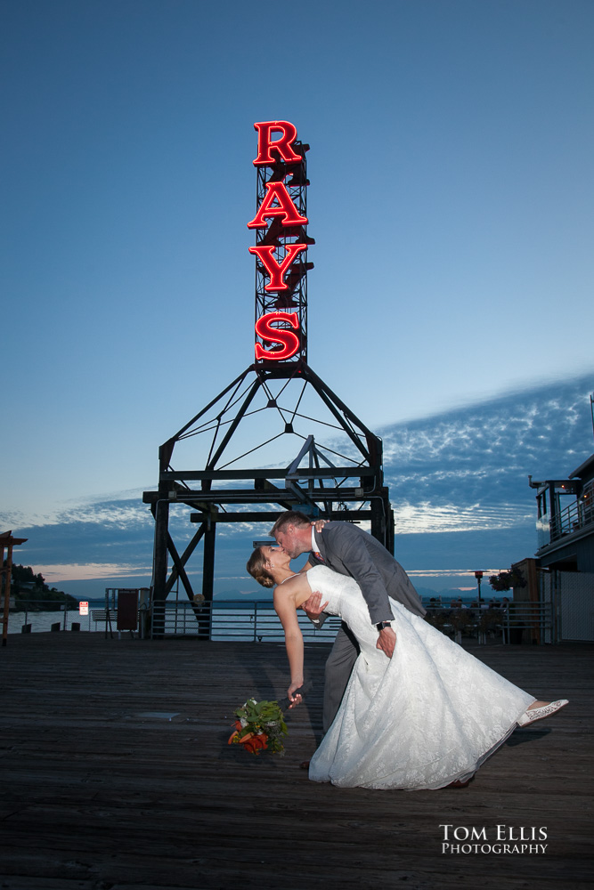 Groom dips his bride for a sunset kiss in front of the iconic neon sign at Ray's Boathouse in Seattle