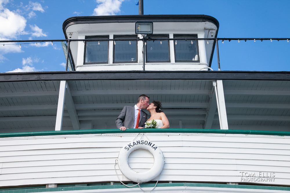 Bride and groom kiss while standing on the upper deck of the Skansonia Ferry during their Seattle area wedding