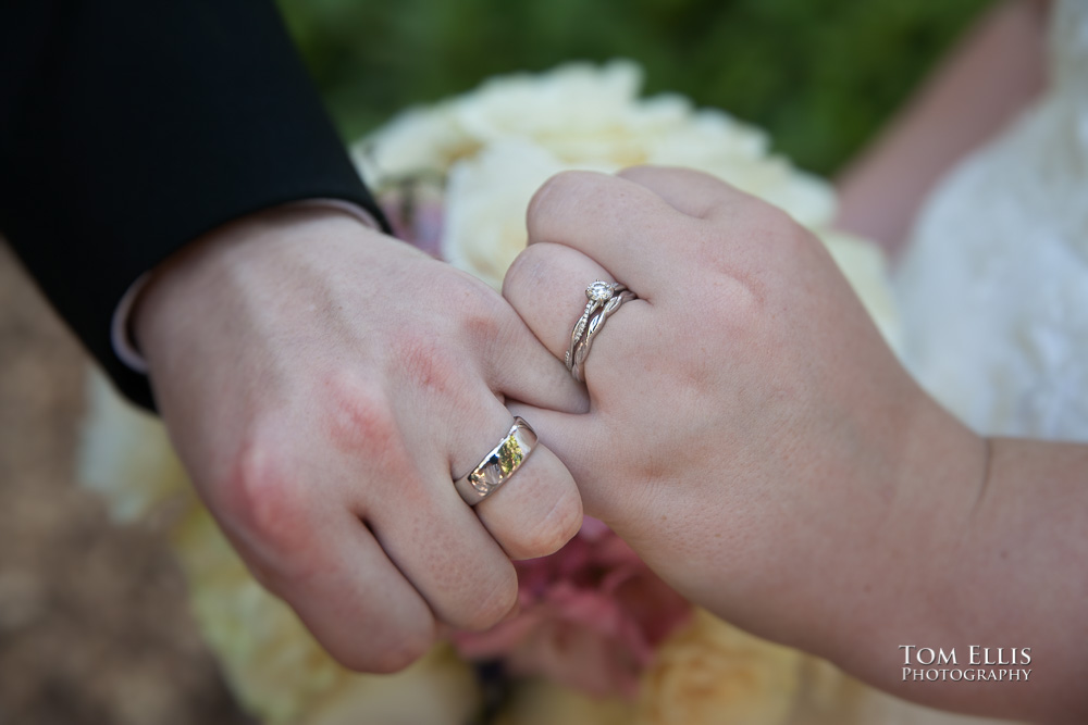 Close up photo of the hands and rings of the bride and groom, as they lock pinkies
