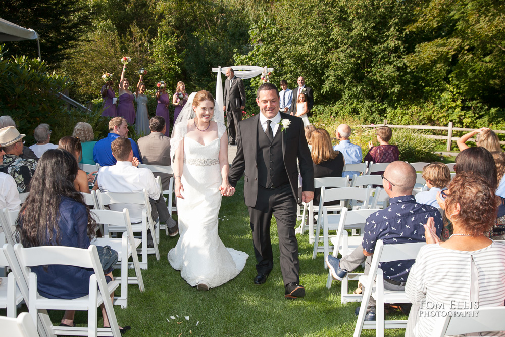 Bride and groom recess down the aisle at the conclusion of the Seattle area wedding ceremony at Tibbetts Creek Manor in Issaquah, photographed by Tom Ellis Photography