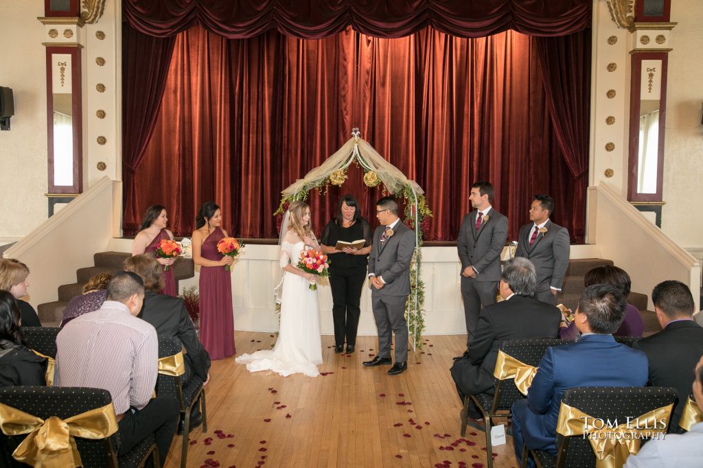 Wedding ceremony, showing wedding party and guests, photographed from the back of the room
