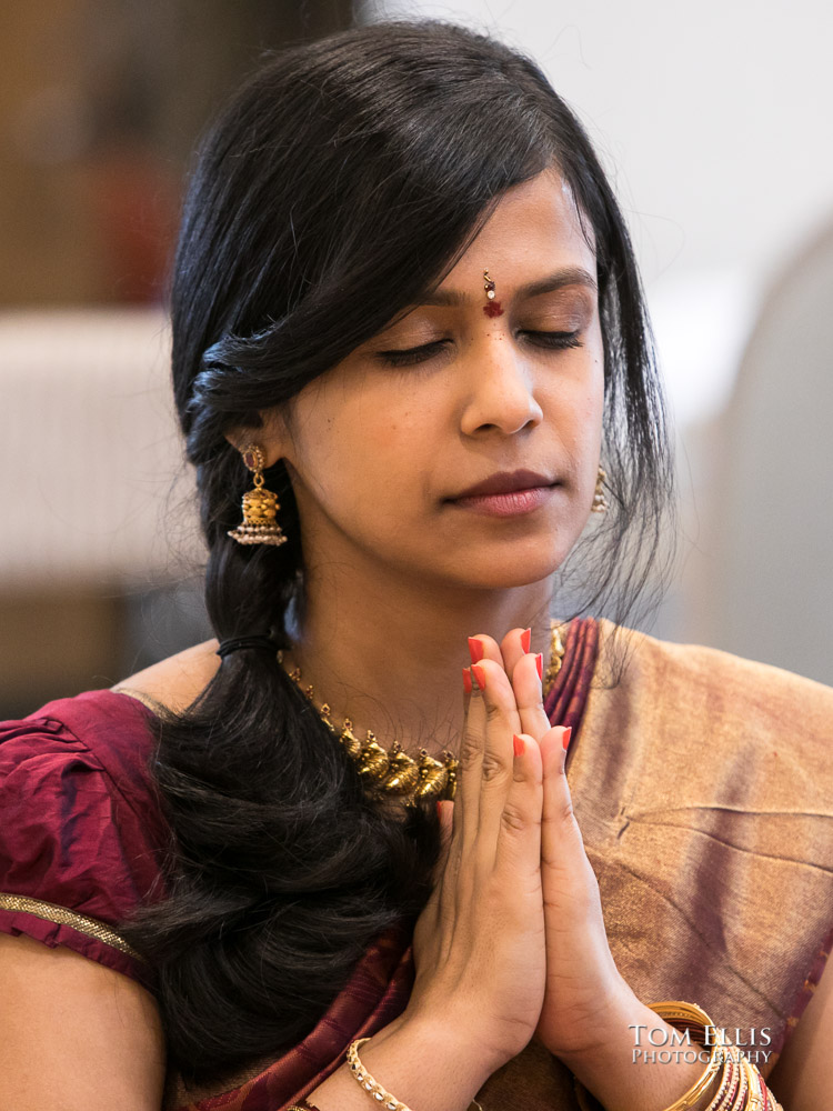 Close up photo of bride at Indian wedding ceremony, as she sits with her eyes closed and hands clasped in front of her face