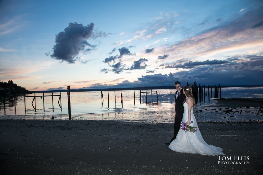 Romantic photo of bride and groom walking along a beautiful Seattle beach at sunset after their Seattle wedding at Ray's Boathouse