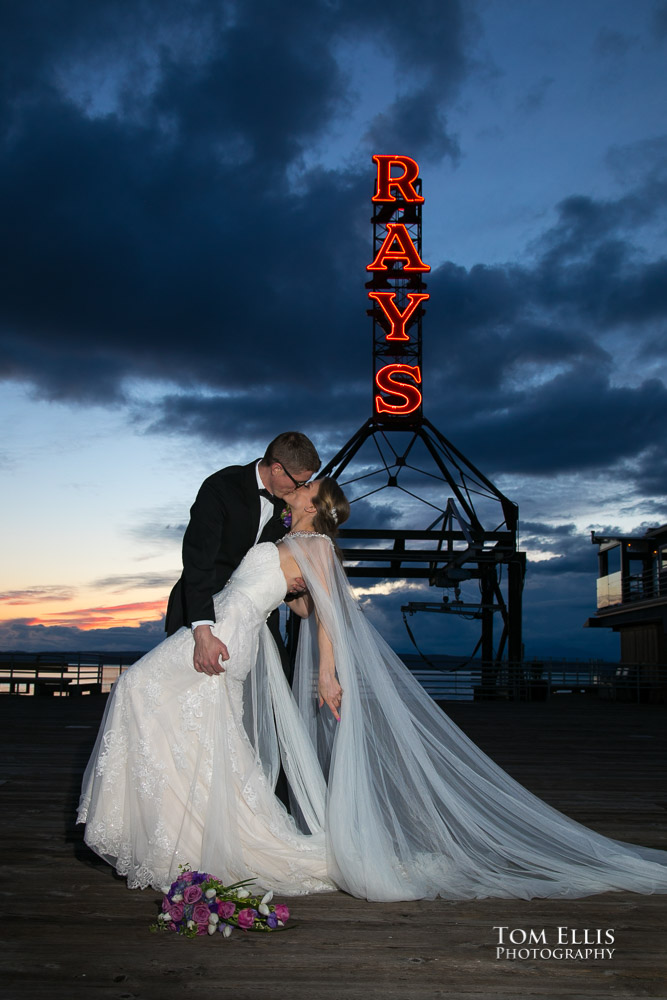 Bride and groom kiss in front of the Ray's Boathouse neon sign during their wedding reception. Tom Ellis Photography, Seattle wedding photographer