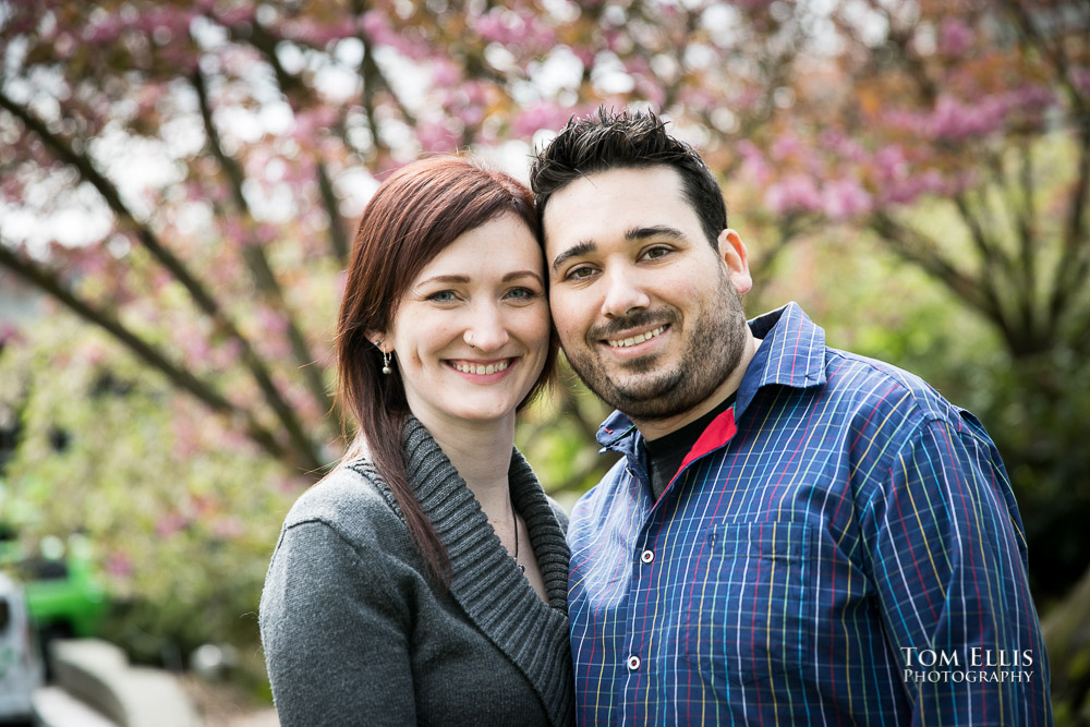 Close up photo of engaged couple standing in front of a flowering cherry tree at Seattle Center during their engagement photo session