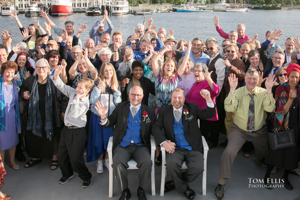 Gay couple pose with all of the guests at their wedding reception on the stern of a cruise ship on Lake Washington after their same-sex Seattle wedding