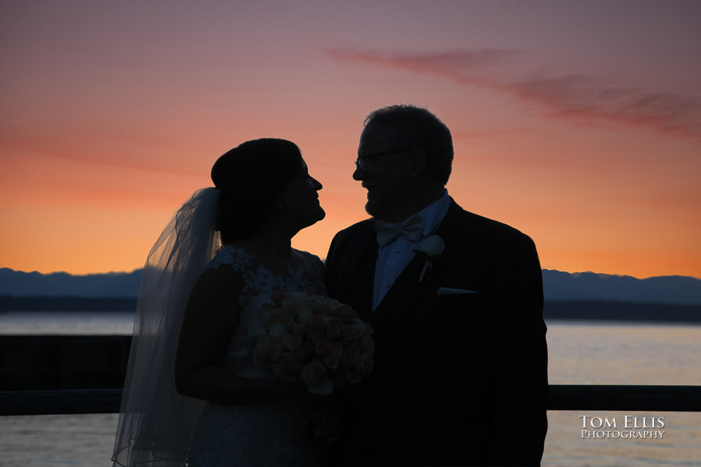 Bride and groom in silhouette against a gorgeous sunset over Puget Sound and the Olympic Mountains