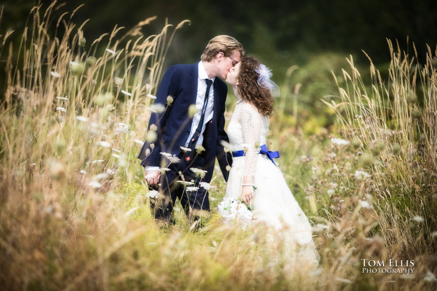 Romantic photo of Bride and groom sharing a kiss while standing in a field of tall grass at Seattle's Magnuson Park