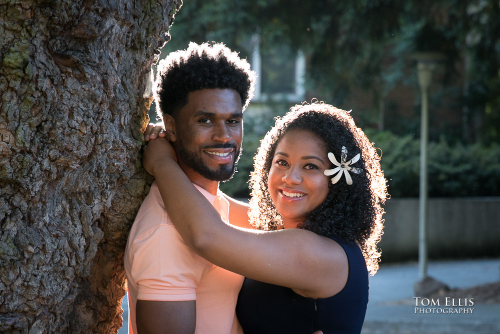 close up photo of engaged couple as they look at the camera, with beautiful backlight providing a halo effect