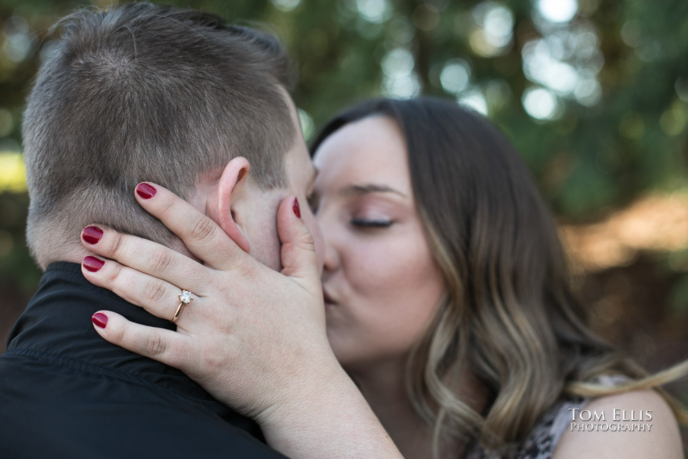 Close up of engagement ring and kiss during their engagement photo session at Gas Works Park