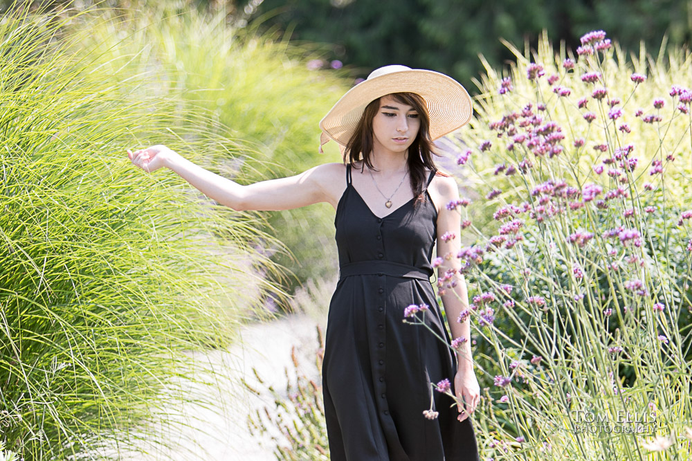 Beautiful high school senior girl walking in a flower garden during her senior photo session at Bellevue Botanical Gardens