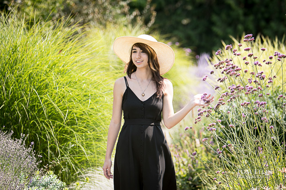 Beautiful high school senior girl walking in a flower garden during her senior photo session at Bellevue Botanical Gardens