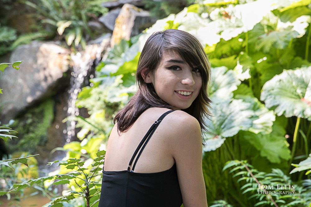 Beautiful high school senior girl walking near a waterfall during her senior photo session at Bellevue Botanical Gardens