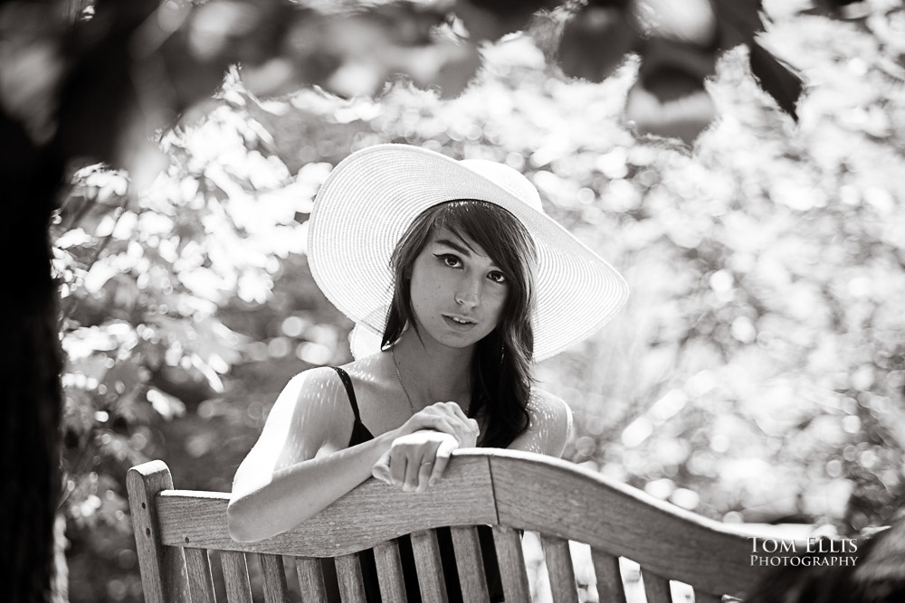 Black and white photo of a beautiful high school senior girl sitting on a bench in the woods, with gorgeous backlighting, Seattle senior photography, Tom Ellis Photography