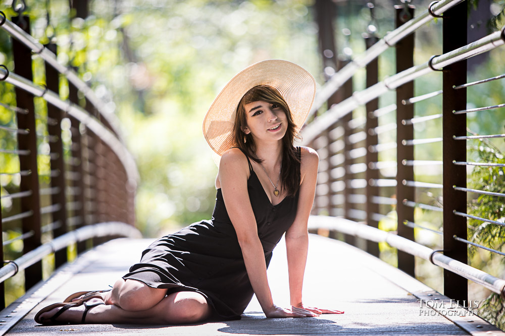 Beautiful high school senior girl sitting on a suspension bridge during her senior photo session at Bellevue Botanical Gardens