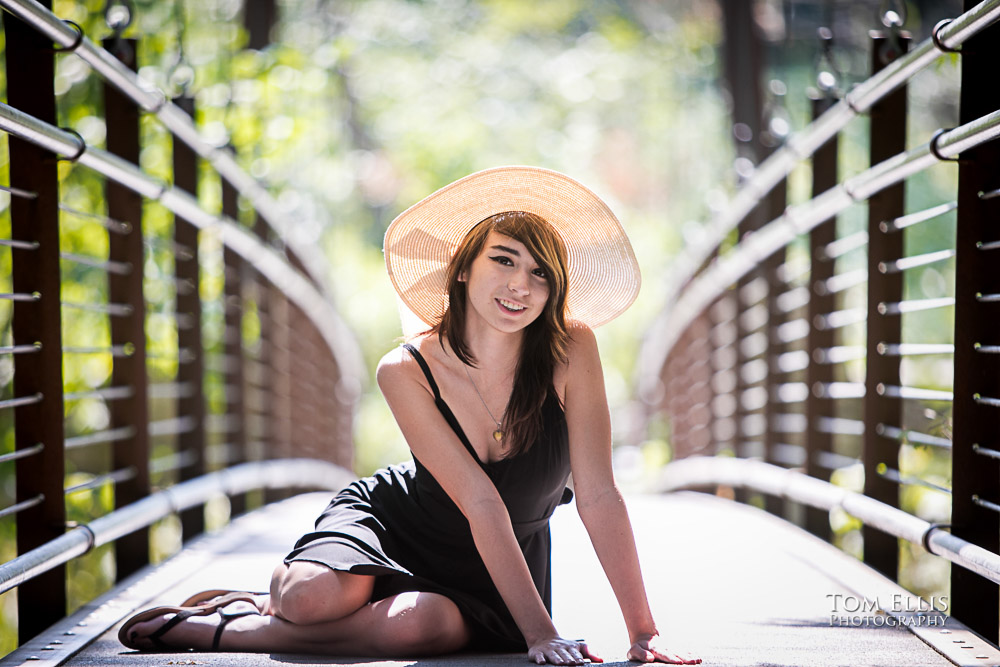 Beautiful high school senior girl sitting on a suspension bridge during her senior photo session at Bellevue Botanical Gardens