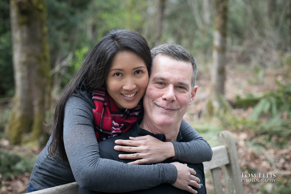 Close up photo as Elaina hugs her fiance Trip while showing off her engagement ring, during our Seattle area engagement photo session at the Bellevue Botanical Garden. Tom Ellis Photography, Seattle engagement photographer