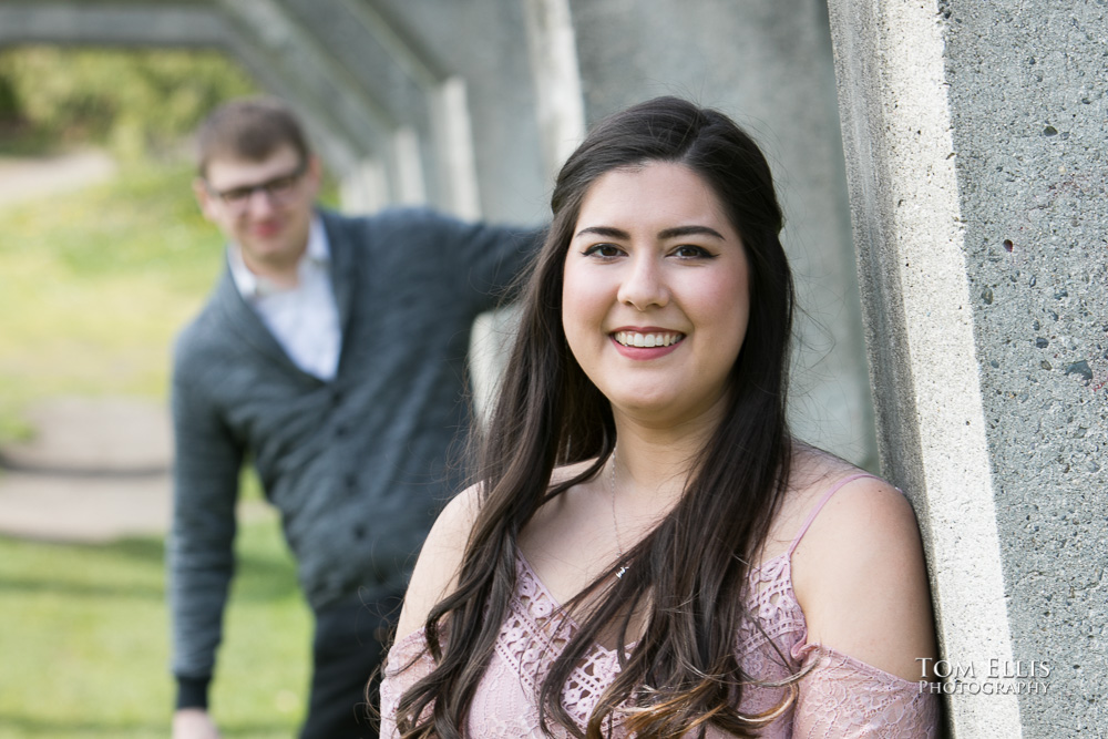Yoshimi looks beautiful while Jacob pops out from behind one of the old arches during their engagement photo session at Gas Works Park. Tom Ellis Photography, Seattle engagement photographer