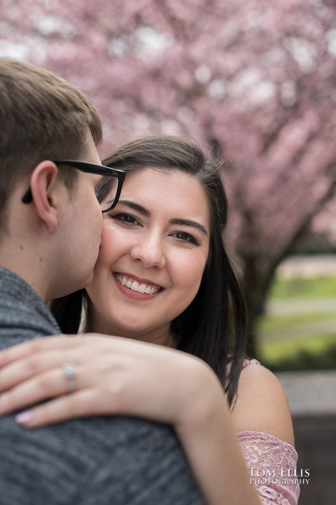 Close up photo of Yoshimi and Jake with the cherry trees during their engagement photo session at the UW campus