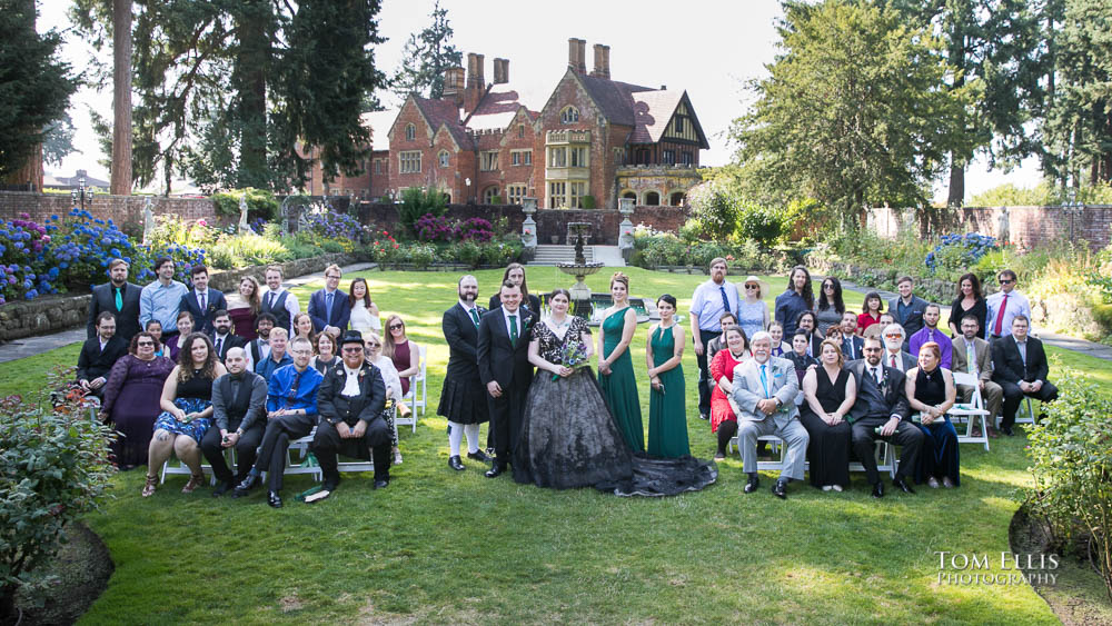 Lisa, Mike and all of their wedding party and guests pose for a photo in the formal gardens at Thornewood Castle, which is visible in the background. Tom Ellis Photography