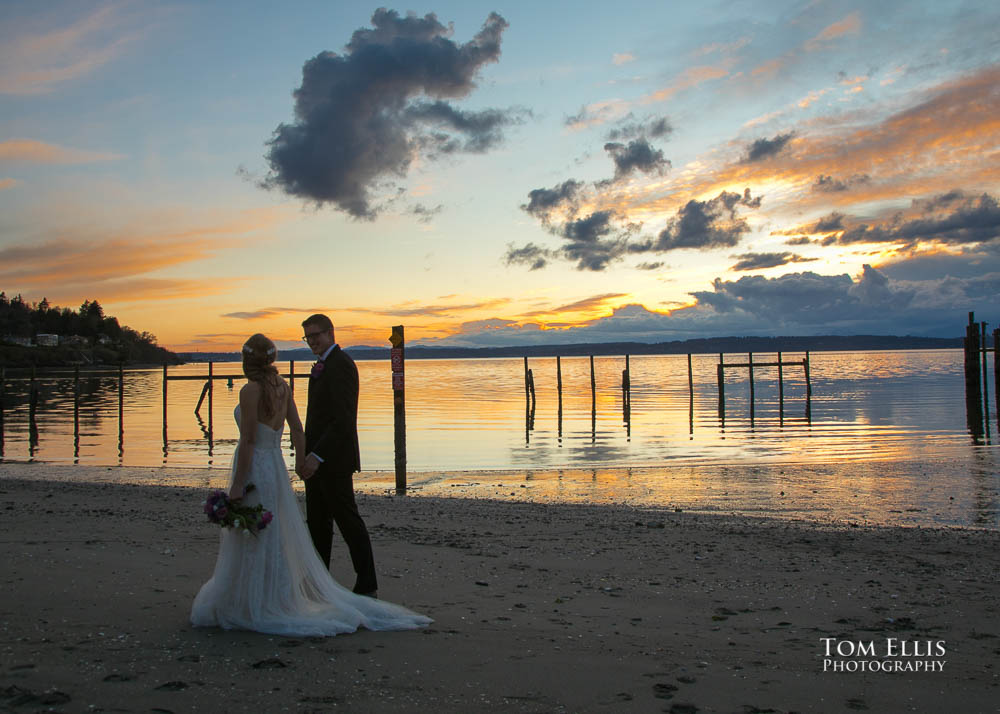 Bride and groon stroll along the beach at sunset during their Seattle wedding at Ray's Boathouse. Tom Ellis Photography
