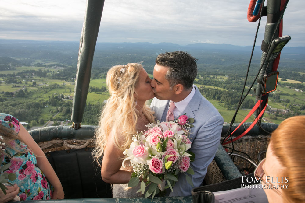 Bride and groom kiss at the conclusion of their elopement wedding ceremony, held,in a hot-air balloon. Tom Ellis Photography, Seattle adventure elopement wedding photographer