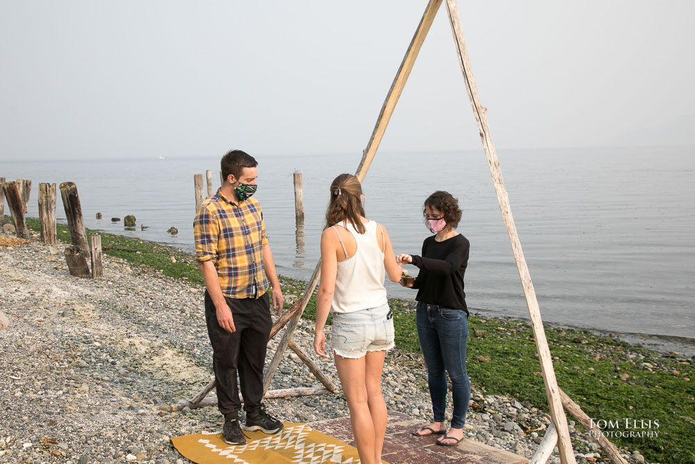 Dan and Catie stand under their wedding arch during their smoky wedding rehearsal on Vashon Island