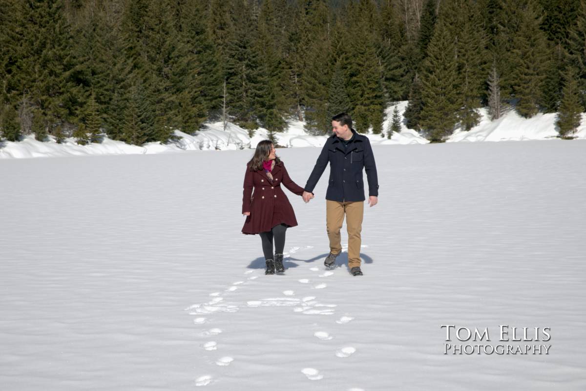 Jessica and Ryan walk across frozen Gold Creek Pond during our snowy engagement photo session. Tom Ellis Photography, Seattle wedding and engagement photographer